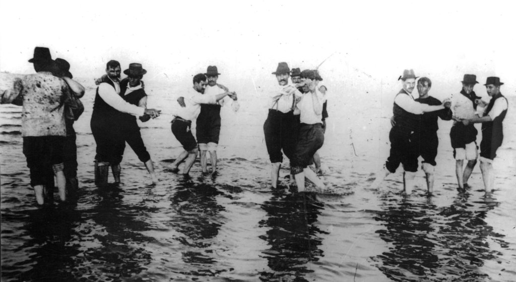 Hombres bailando tango en la orilla del río.